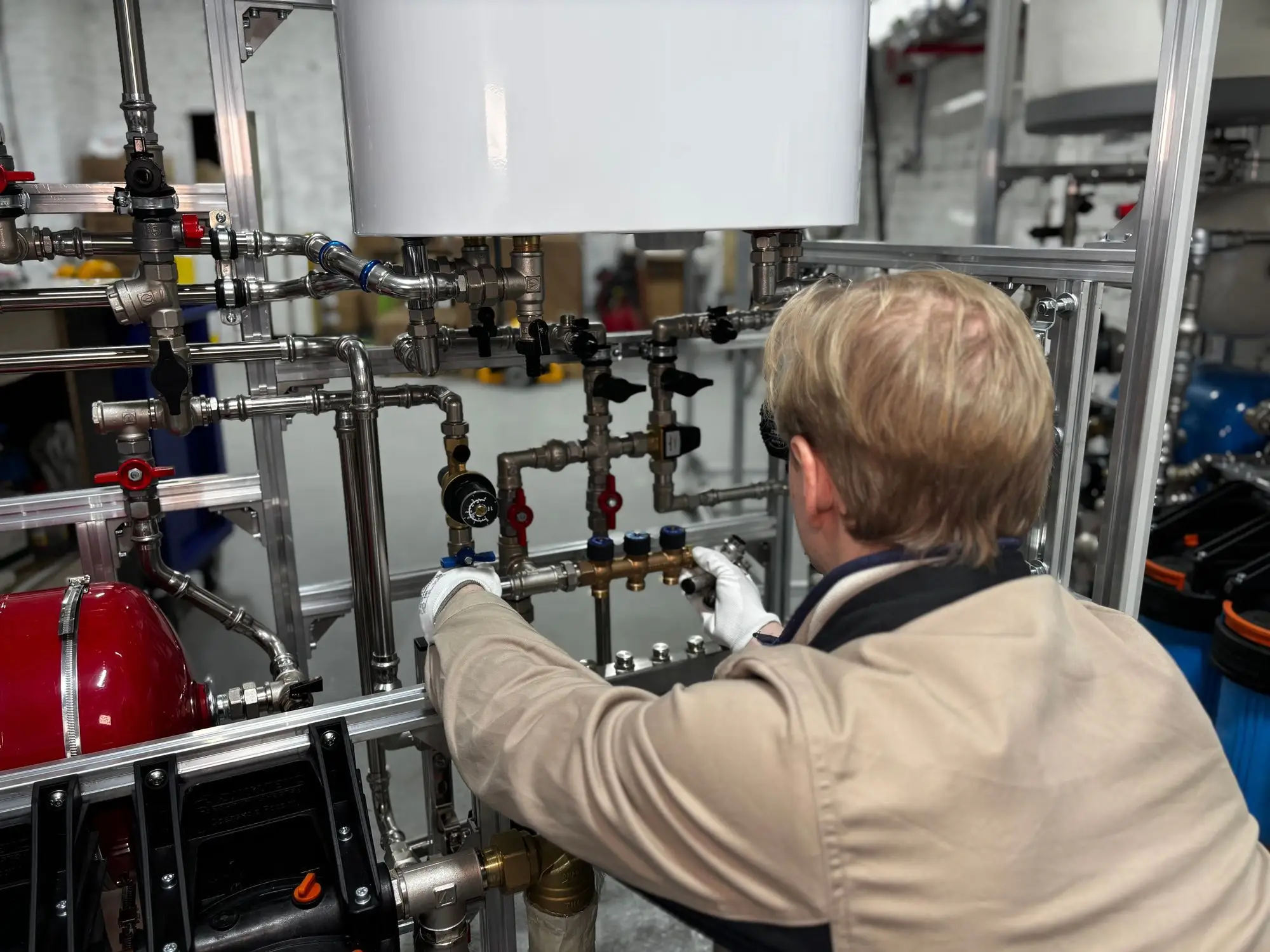 Technicien de dos ajustant des vannes sur un montage de tuyauterie