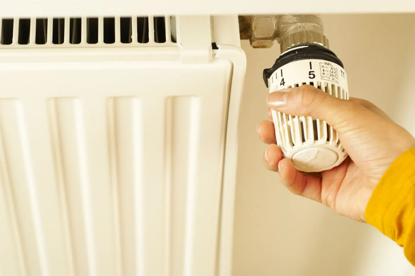 Main réglant une tête thermostatique de radiateur