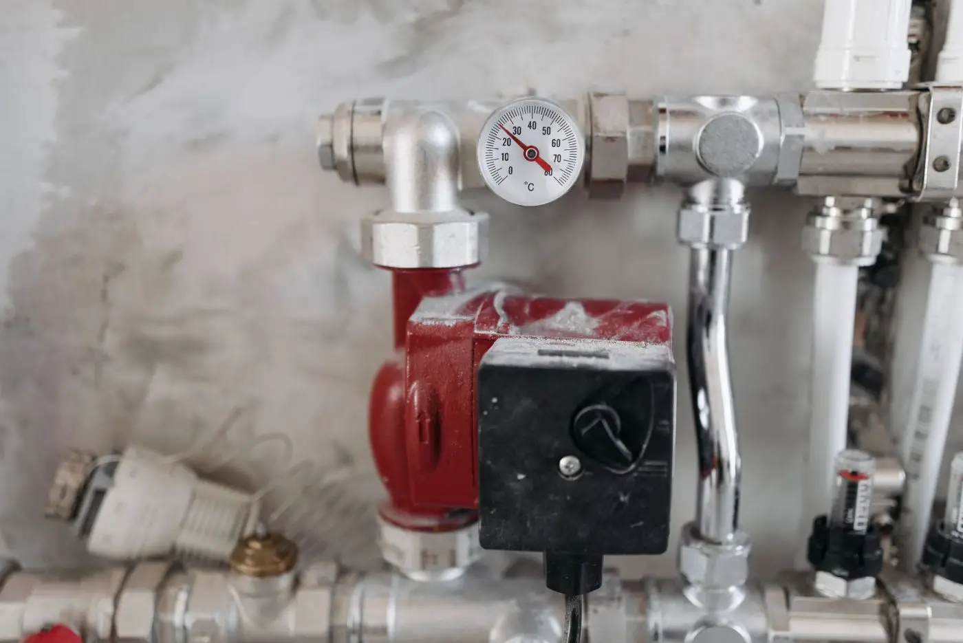 Thermomètre et circulateur rouge sur tuyaux chromés