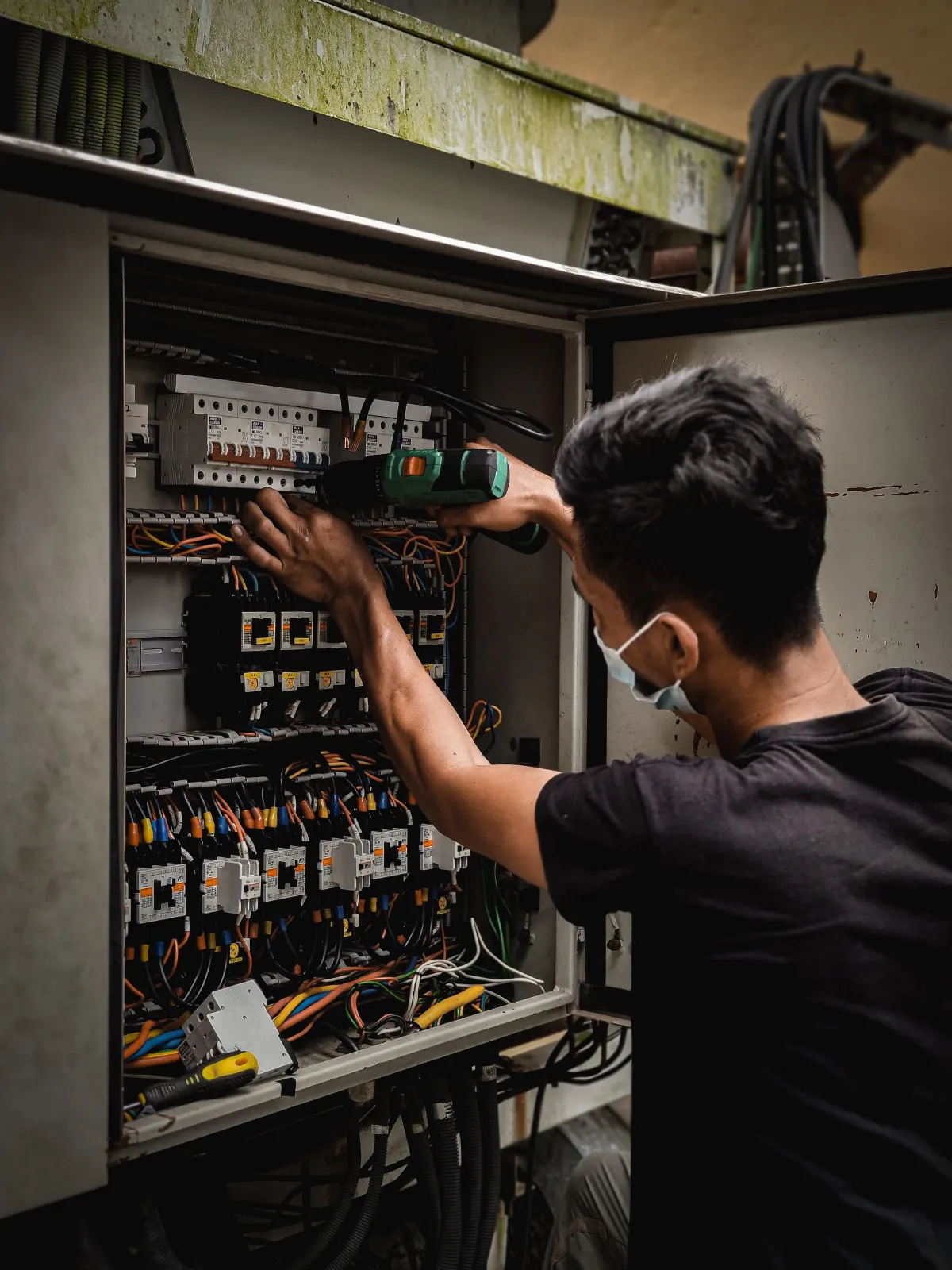 Électricien intervenant sur un tableau mural