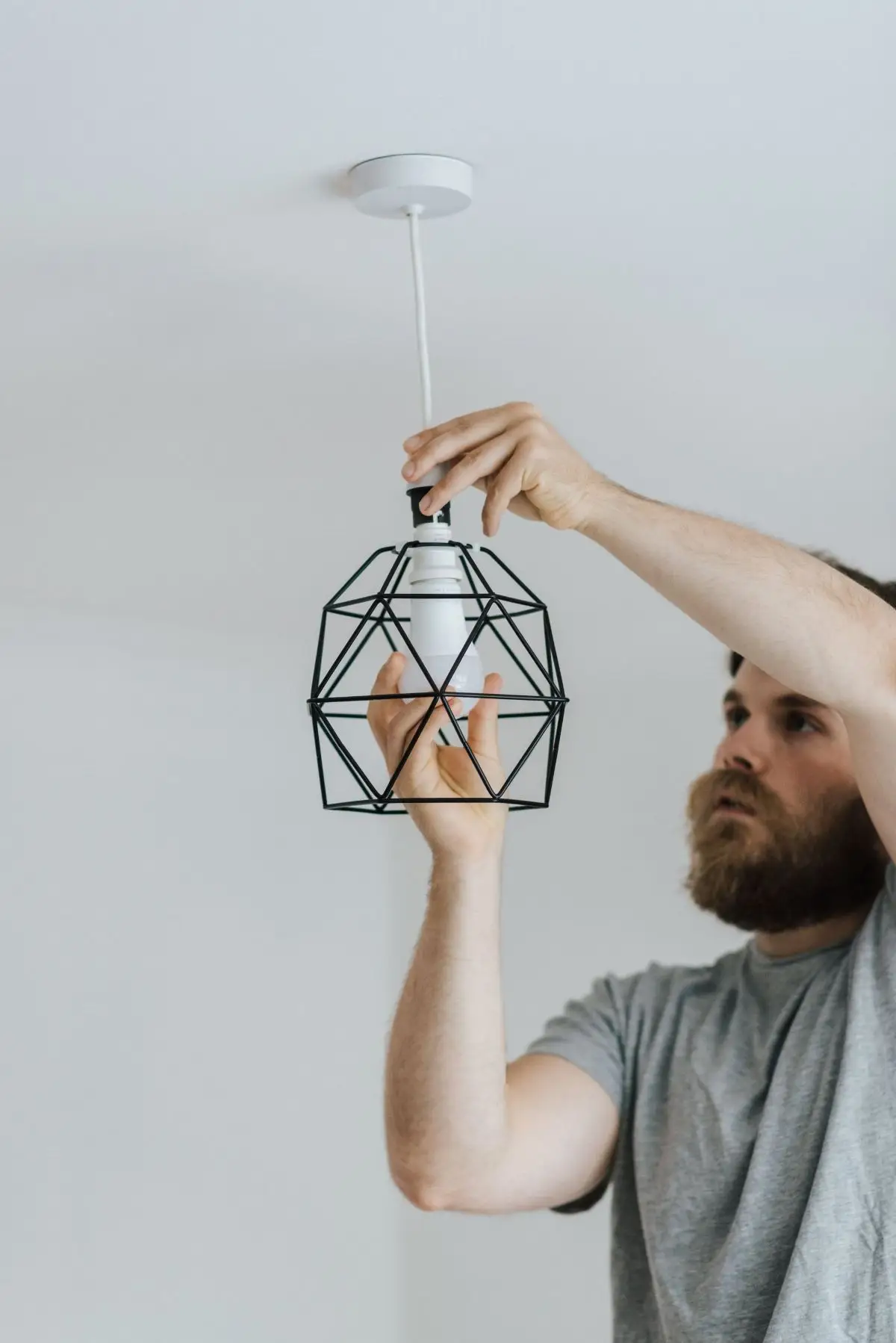 Homme installant une ampoule dans une suspension métallique