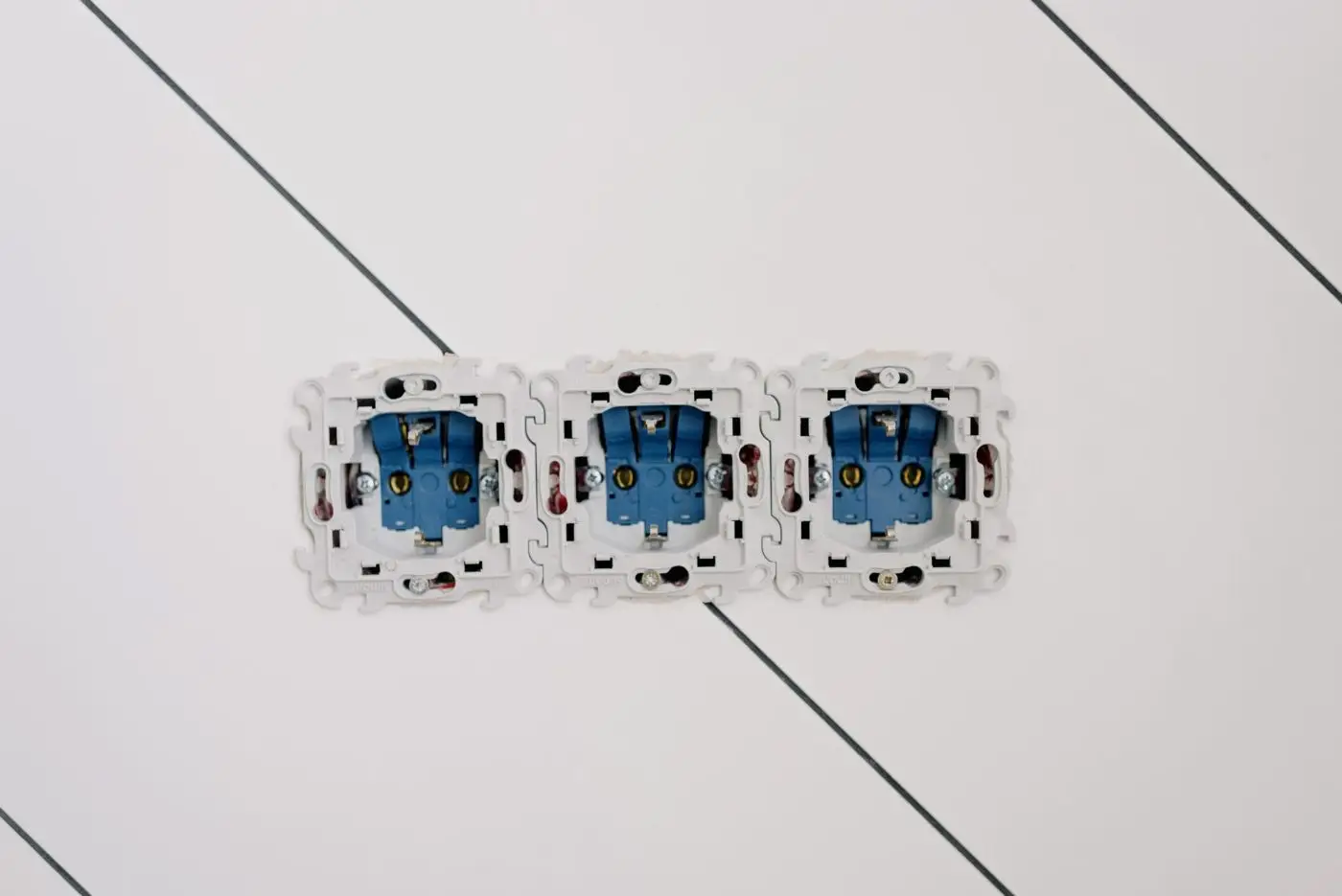 Trois mécanismes de prises de courant sur un mur blanc