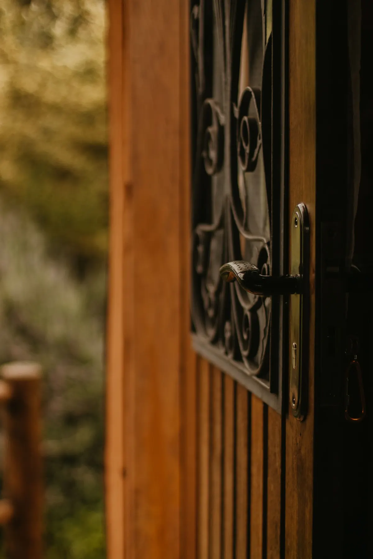 Porte en bois entrouverte avec grille en fer forgé et poignée noire