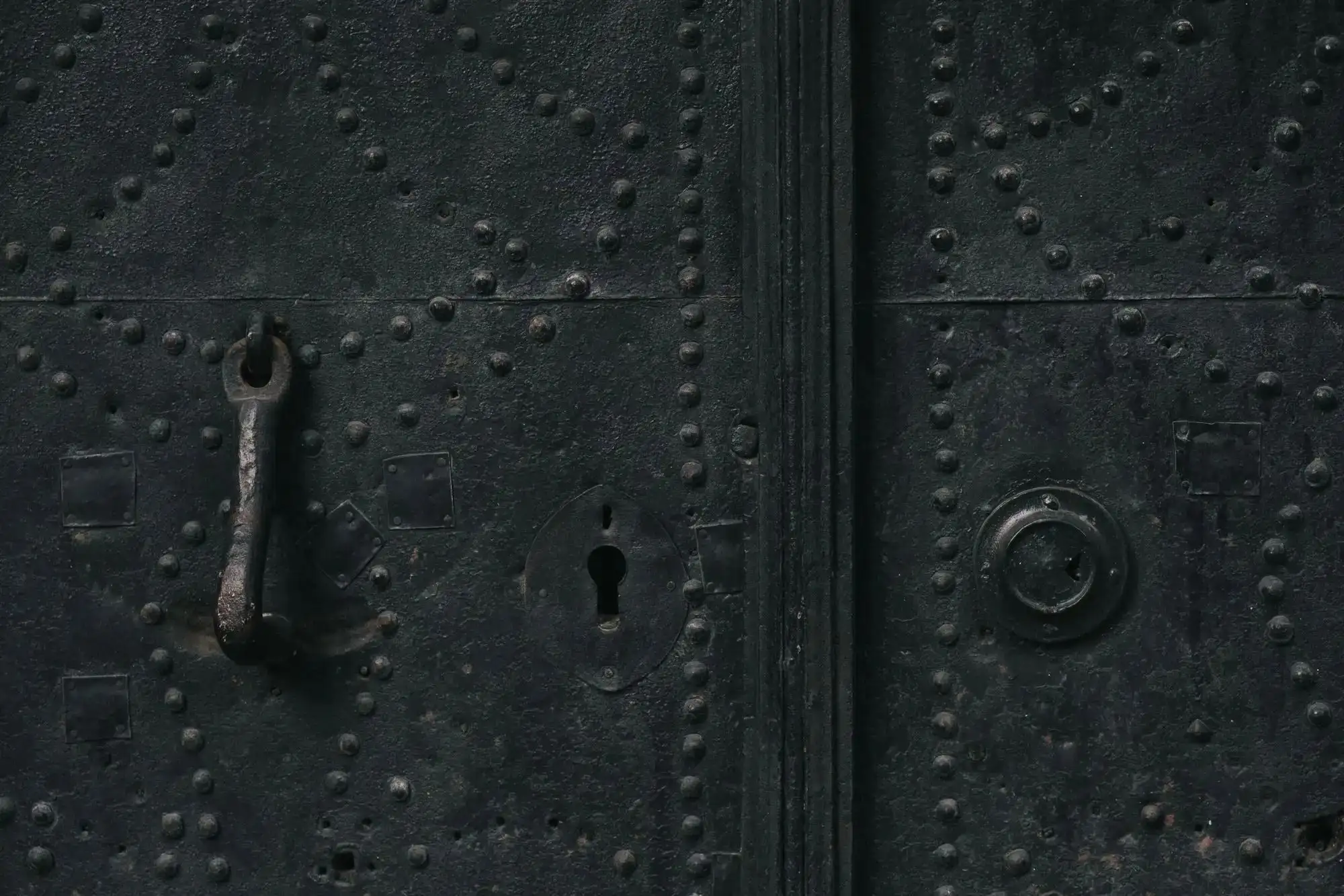 Porte métallique noire cloutée, poignée et entrée de serrure